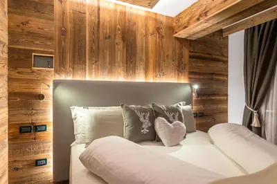 a bed in a room with wooden walls at Alpstyle Hotel Albolina Wellness & Beauty in Canazei