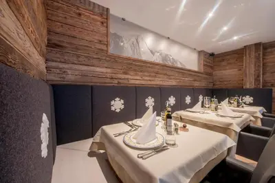 a restaurant with three tables with white table settings at Alpstyle Hotel Albolina Wellness & Beauty in Canazei