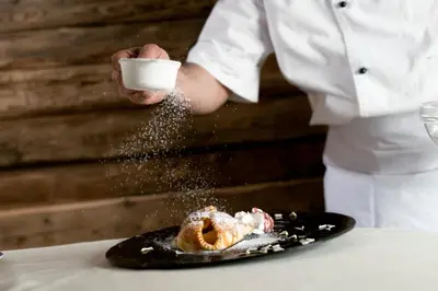 a chef is sprinkling powdered sugar on a doughnut at Alpstyle Hotel Albolina Wellness & Beauty in Canazei