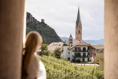 a woman looking out a window at a church at Weingarten Terlan - Rooms & Breakfast in Terlano