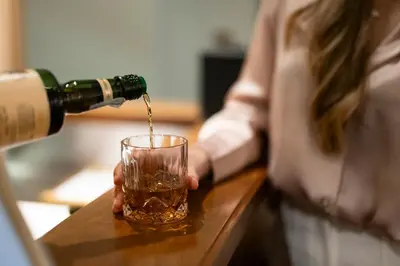 a woman pouring a drink into a glass at Weingarten Terlan - Rooms & Breakfast in Terlano
