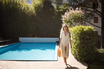 a woman in a white dress walking by a pool at Weingarten Terlan - Rooms & Breakfast in Terlano