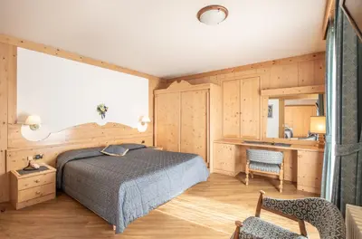 a bedroom with a bed and a desk at Hotel San Martino in San Martino di Castrozza