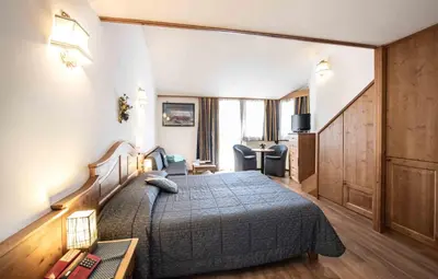 a bedroom with a bed and a desk and a chair at Hotel San Martino in San Martino di Castrozza