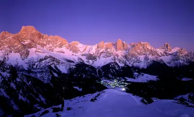 a snow covered mountain with a town in front of it at Hotel San Martino in San Martino di Castrozza
