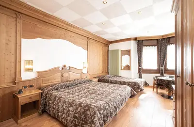 a bedroom with two beds and a table at Hotel San Martino in San Martino di Castrozza