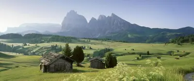 an old house in a green field with mountains at Residence Granvara in Ortisei