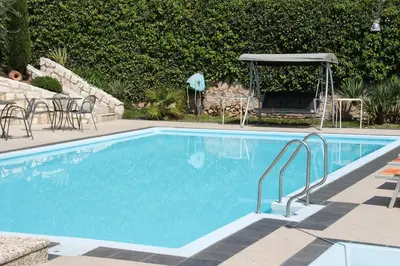 a swimming pool with chairs and a table and an umbrella at Garni Brunnenhof in Caldaro