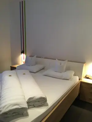two beds in a room with white sheets and pillows at Garni Brunnenhof in Caldaro
