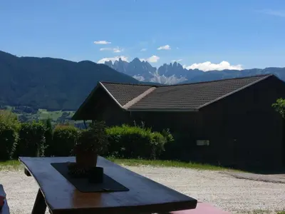 a black barn with a table in front of it with mountains at Biogasthaus Plonerhof 