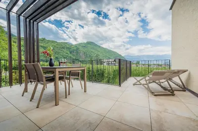 a patio with a table and chairs and mountains at Sinnergut in Nalles