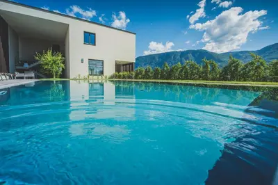 a swimming pool in front of a house with mountains at Sinnergut in Nalles