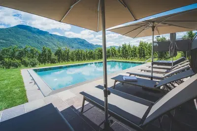 a pool with two lounge chairs and an umbrella at Sinnergut in Nalles