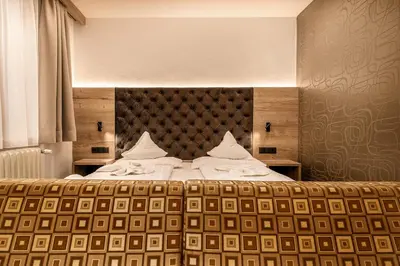 a bedroom with a large bed with a headboard at Hotel Klammer in Vipiteno