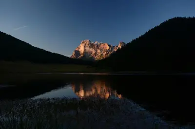 a mountain reflection in a lake in the middle of a forest at Lausen Vil in Canale San Bovo