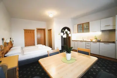 a room with a bed and a table and a kitchen at Garnì La Dorada in Colfosco