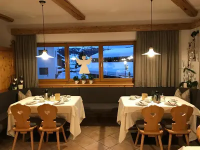 two tables in a restaurant with a woman in the window at Garnì La Dorada in Colfosco