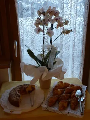 a table with some pastries and a vase with flowers at Garnì La Dorada in Colfosco