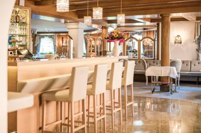 a bar with white chairs in a restaurant at Hotel Funggashof in Naturno