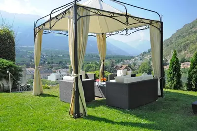 a gazebo with chairs and a table in the grass at Hotel Funggashof in Naturno
