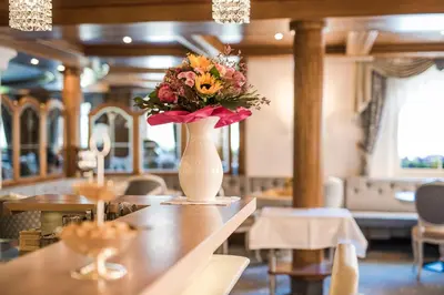 a vase with flowers on a table in a restaurant at Hotel Funggashof in Naturno