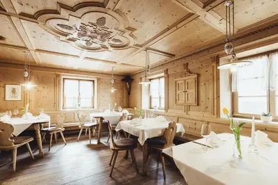 a restaurant with tables and chairs and a chandelier at Hotel Schmuckhof in Chiusa