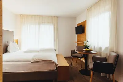 a bedroom with a bed and a table and chairs at Hotel Schmuckhof in Chiusa