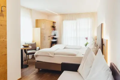 a hotel room with two beds and a table at Hotel Schmuckhof in Chiusa