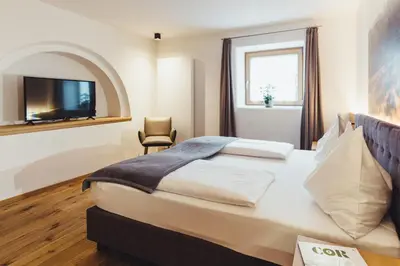 a hotel room with a large bed and a television at Hotel Schmuckhof in Chiusa