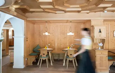 a person walking past a dining room with tables and chairs at Hotel Erzherzog Johann in Schenna