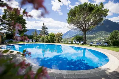a large swimming pool with mountains in the background at Hotel Erzherzog Johann in Schenna