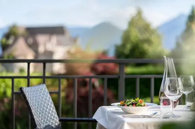 a table with a bowl of salad and wine glasses at Hotel Erzherzog Johann in Schenna