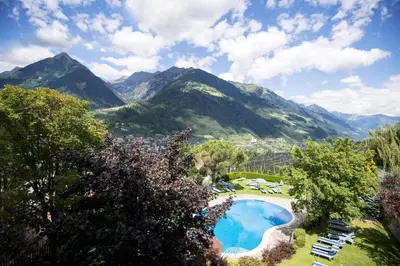 a resort with a pool and mountains in the background at Hotel Erzherzog Johann in Schenna