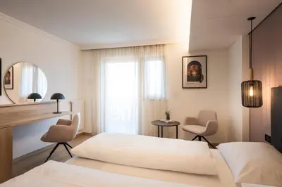 a bedroom with a bed and two chairs and a window at Hotel Erzherzog Johann in Schenna
