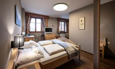 a bedroom with a bed and a couch and a television at Hotel Zum Turm in Castelrotto