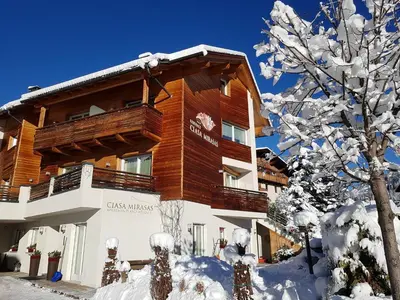 a large wooden building in the snow at Residence Ciasa Mirasas in Badia