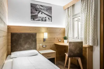 a hotel room with a bed and a desk at Pensione Vittoria in Colfosco