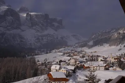 a village covered in snow with a mountain in the background at Pensione Vittoria in Colfosco