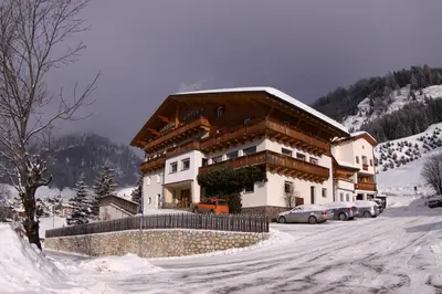 a building in the snow with cars parked in front at Pensione Vittoria in Colfosco
