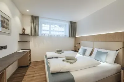 a bedroom with two beds and a large window at Apartment Villa Stefania in Selva di Val Gardena