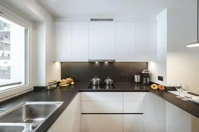 a kitchen with white cabinets and a sink at Apartment Villa Stefania in Selva di Val Gardena