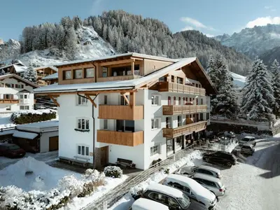 a building with cars parked in a parking lot at Apartment Villa Stefania in Selva di Val Gardena