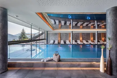 a swimming pool in a building with a large window at Hotel Edelweiss in Maranza