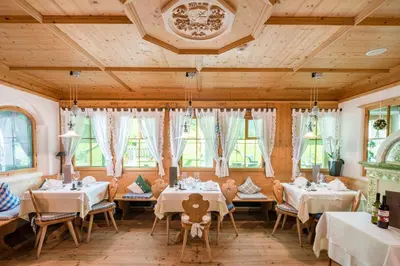 a dining room with tables and chairs and windows at Hotel Erika in Braies