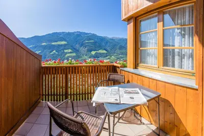 a table and chairs on a balcony with mountains at Gasthof Falkenstein in Naturno
