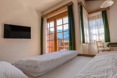 a bedroom with two beds and a large window at Gasthof Falkenstein in Naturno