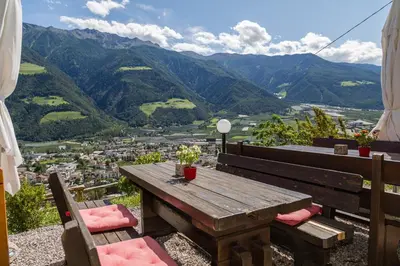 a wooden table with two chairs and a view of a city at Gasthof Falkenstein in Naturno