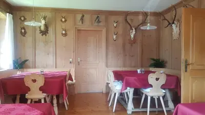 a dining room with two tables with red tablecloths at Gasthof Falkenstein in Naturno