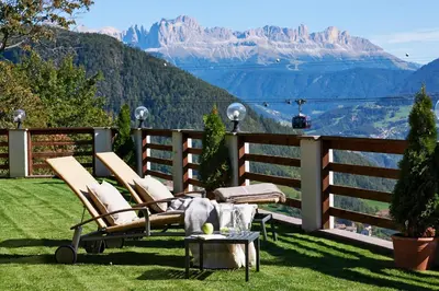 a balcony with chairs and a table and mountains at Chalet Grumer Suites&Spa in Soprabolzano