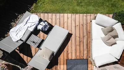 a couple of chairs and tables on a wooden deck at Chalet Grumer Suites&Spa in Soprabolzano